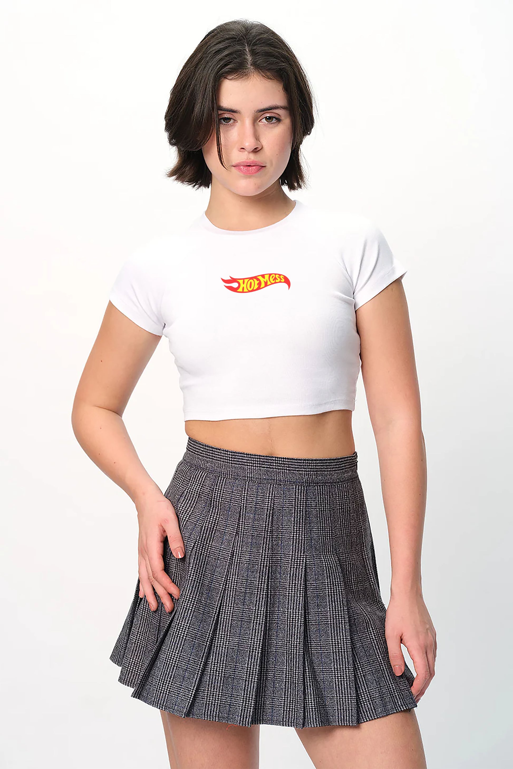 spankers Woman wearing a white crop top with a logo and a pleated skirt on a white background